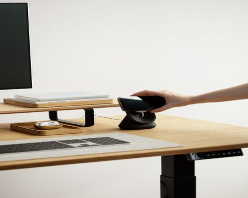 Person adjusting monitor height on a well organized desk