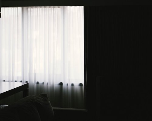 A well lit interior space with soft curtains managing harsh sunlight